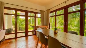 Un comedor con mesa y sillas y ventanas. en Tropical garden, en Phuket