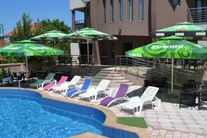 a group of lawn chairs and umbrellas next to a pool at Guesthouse Vila DND in Niška Banja