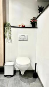 a white bathroom with a toilet and plants at La Maison Attila en Ardennes in Libin