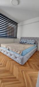 a large bed in a room with a wooden floor at Stan na dan - Apartmani Q in Doboj