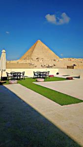 um grupo de mesas de piquenique e um guarda-chuva em frente a uma pirâmide em Solima Pyramids View no Cairo