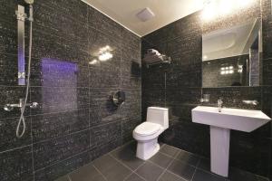 a black tiled bathroom with a toilet and a sink at Carlton Hotel in Incheon