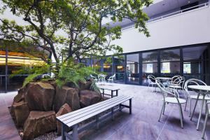 a building with a tree and tables and chairs at KABIN Kyoto in Kyoto