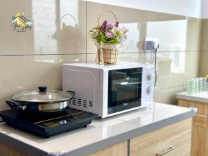 a microwave on a counter with a basket of flowers at Amber Cove 7pax/VideoGame/5min to Jonker in Melaka