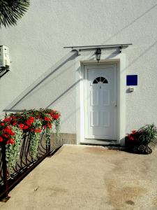 a white door on a white building with red flowers at Apartment Sea Garden in Ičići