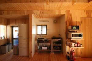 a kitchen with wooden walls and wooden floors at Hostel Fish in a River in Takayama