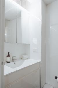 a white bathroom with a sink and a mirror at Cosy studio with a big view in Sydney