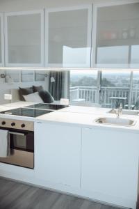 a kitchen with white cabinets and a stove and sink at Cosy studio with a big view in Sydney