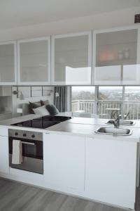 cocina con armarios blancos y encimera en Cosy studio with a big view en Sídney