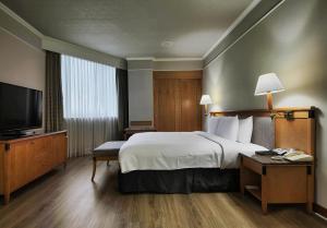 a hotel room with a bed and a flat screen tv at The Carlton Hotel Hsinchu in Hsinchu City