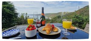 a table with a plate of food and two glasses of orange juice at Polhawn Lookout, The Forgotten Chalet in Cawsand