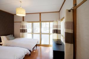 a bedroom with two beds and a large window at Hakuba Forest House in Hakuba +3 photos
