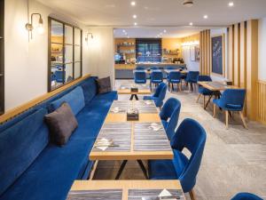 a restaurant with a blue couch and tables and chairs at Hotel Sielminger Hof in Filderstadt