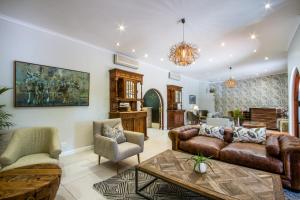 a living room with a couch and chairs and a table at Hlangana Lodge in Oudtshoorn