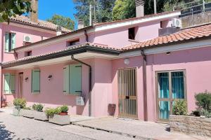 una casa rosa con persianas verdes en una calle en Casa Rosa, en Teolo