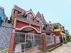 een rood huis met een hek ervoor bij OYO Life 92546 Kost Merah Bojongsoang Syariah in Bandung