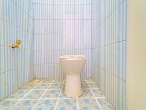 een badkamer met een toilet in een blauwe betegelde muur bij OYO Life 92546 Kost Merah Bojongsoang Syariah in Bandung
