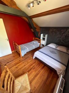 Bas-en-BassetにあるChambres des arrysの赤い壁とウッドフロアの客室で、ベッド2台が備わります。