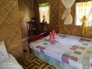 a bedroom with a bed with pink shoes on it at Shirley's Cottage - Pamilacan Island in Baclayon