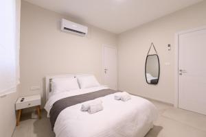 ein weißes Schlafzimmer mit einem Bett und einem Spiegel in der Unterkunft דירת נופש התבור Hatvor condo in Shadmot Devora