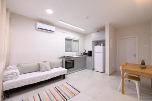 ein Wohnzimmer mit einem weißen Sofa und einer Küche in der Unterkunft דירת נופש התבור Hatvor condo in Shadmot Devora