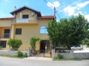 a yellow house with a tree in front of it at Apartments Stana in Sukošan