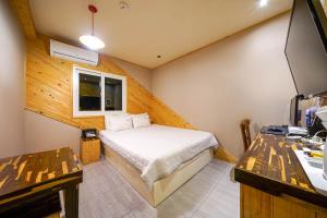 Habitación pequeña con cama y escritorio. en Oops Hotel en Busan