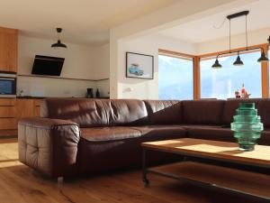 a brown leather couch in a living room with a table at Exclusive chalet with sauna and unique view of the glacier in Neukirchen am Großvenediger