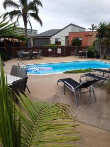 una piscina con sillas, mesa y sillas en The Lakes Apartments, en Lakes Entrance