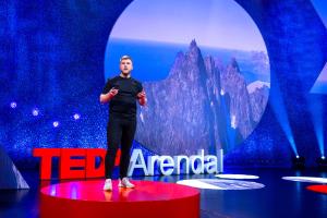 a man standing on top of a red oval stage at For Groups & Families - FREE Parking & Near Attractions in Tromsø