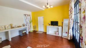 a living room with yellow walls and wooden floors at Laemsing Whitehouse Resort in Laem Sing