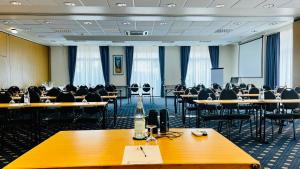 una sala de conferencias con mesas y sillas. en Konferenzhotel Ysenburger Hof, en Langenselbold