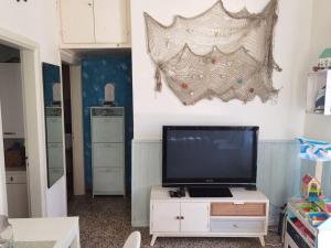 a living room with a television on a white cabinet at La piccola oasi tra sole e mare in Ceriale