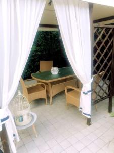a patio with a green table and chairs and curtains at La piccola oasi tra sole e mare in Ceriale
