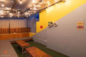 a room with two benches and a yellow wall at Zostel Bangalore- Indiranagar in Bangalore