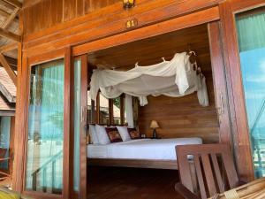 a bed in a wooden room with a canopy at Lipe Beach Resort in Ko Lipe