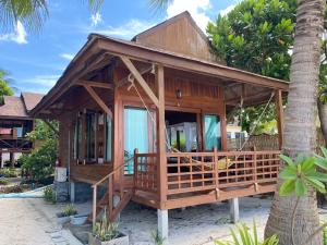 a wooden house on the beach with a palm tree at Lipe Beach Resort in Ko Lipe