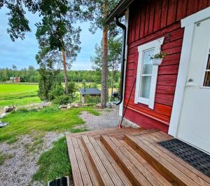 uma casa vermelha com uma porta de madeira e um quintal em Luksusta mökkeilyyn Villa Sörkkä em Metsämaa