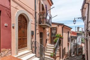 un callejón en un casco antiguo con escaleras y una puerta de madera en Casa Bizzarro, en Deliceto