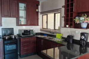 a kitchen with wooden cabinets and a counter top at Holiday Haven in Gaborone