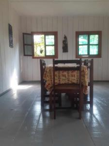 a dining room with a table and two windows at Casa Mãe - Inn in Principe