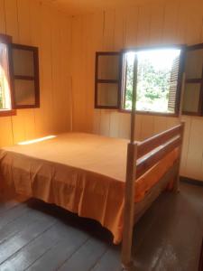 Casa Mãe - Inn في Principe: غرفة نوم بسرير في غرفة بها نافذتين