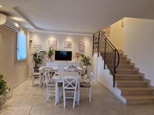 B&B Fiore في Ganfardine: غرفة طعام بها طاولات بيضاء وكراسي ودرج