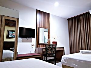 a hotel room with two beds and a desk and a mirror at Hotel S3 Setrasari Bandung in Bandung