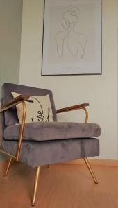 uma cadeira sentada numa sala com um quadro na parede em Le cocon vitréen ! em Vitré