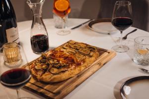 een pizza op een snijplank op een tafel met wijnglazen bij Aparthotel Maso Corto in Maso Corto