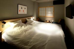 sypialnia z białym łóżkiem z oświetleniem w obiekcie ALPHABED INN Takamatsuekimae w mieście Takamatsu