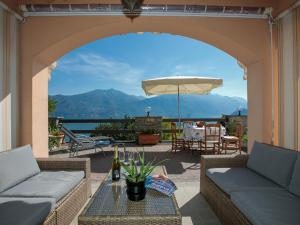 eine Terrasse mit Sofas, einem Tisch und einem Sonnenschirm in der Unterkunft Sonenga Panoramic Terrace in Menaggio