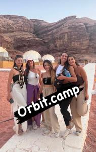 Un gruppo di donne che si trovano davanti a un canyon di Orbit camp a Wadi Rum