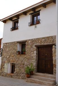 een stenen huis met een houten deur en ramen bij La Casita de los Pájaros in San Martín de Valdeiglesias